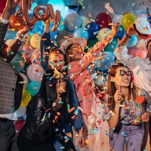 Group of young women and men having fun with balloons and photo booth at a party